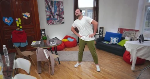Young guy doing workout after work on laptop at home. Break to warmup Stock-Footage 99321776