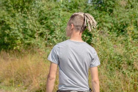 A young guy with dreadlocks in a gray T-shirt on the background of the forest Stock Photos