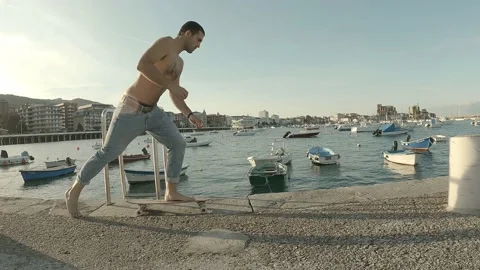 Young guy dressed in jeans and shirtless walks barefoot with a skateboard alo Stock Footage 141678019