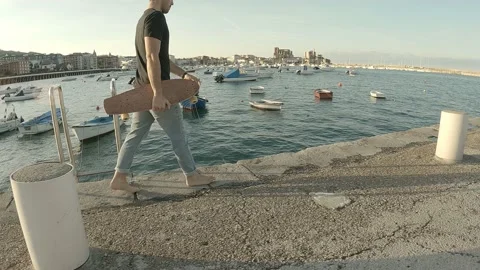 Young guy dressed in jeans and black short sleeve t-shirt walks barefoot with Stock Footage 141678231