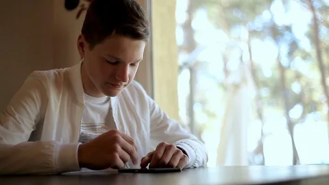 A young guy dressed in white flips through a social media feed on his phone Video stock 113598873