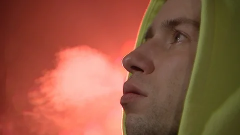 A young guy drinking hot tea or coffee from a red mug, Smoking a cigarette. 動画素材 120577733