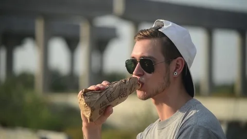 Young guy drinks Beer from a Bottle against concrete construction of Bridge Stock Footage 78960765