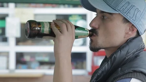 Young guy drinks beer from bottle. c takes a sip from the neck. in profile. Stock-Footage 113792360