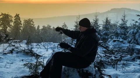 Young guy drinks hot tea from a thermos in the winter morning in the mountains Stock Photos