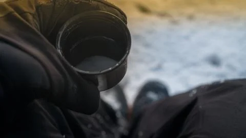 Young guy drinks hot tea from a thermos in the winter morning in the mountains Stock Photos