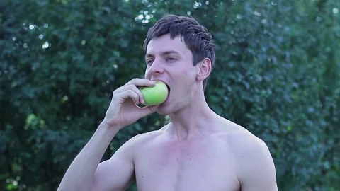 A young guy eating an apple in the garden Video stock 78938400