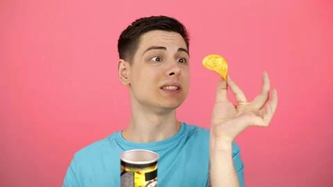 A young guy is eating spicy crisps from a can Stock Footage 166560794