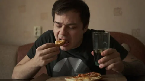 Young guy eats delicious pizza and holds a glass with soda Stock-Footage 149315324