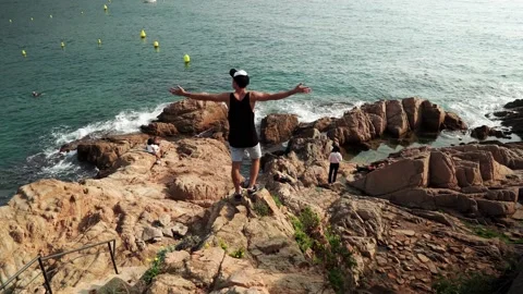 A young guy on the edge of a cliff admiring the sea in Tossa de Mar Video stock 171543587