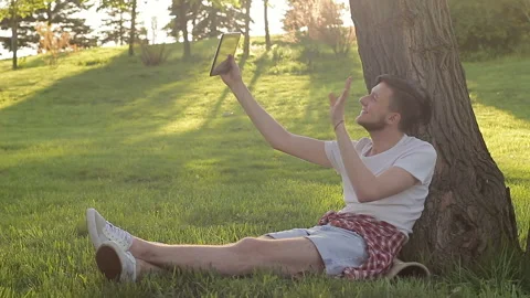 Young guy emotionally communicating in skype on nature Video stock 89452319