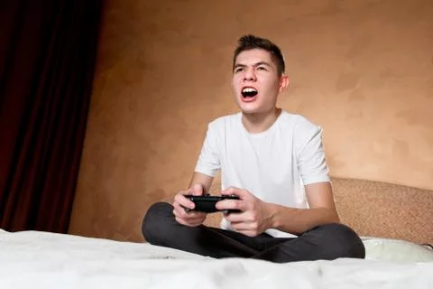 Young guy emotionally plays a computer game with the joystick Stock Photos