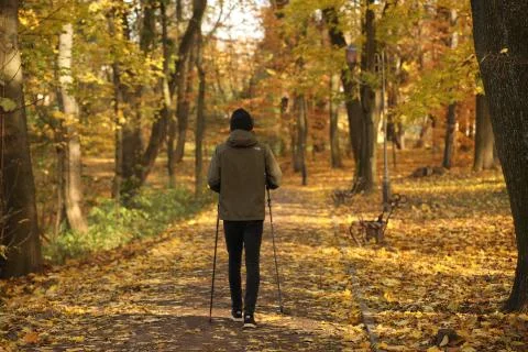 A young guy is engaged in Nordic walking in an autumn park among fallen yello Foto stock