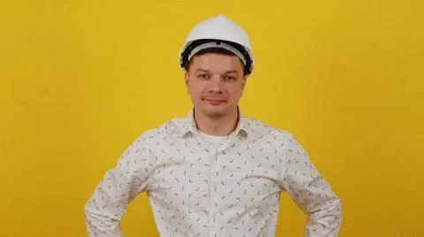 Young guy engineer or worker posing in hardhat and shirt on yellow background Stock Photos