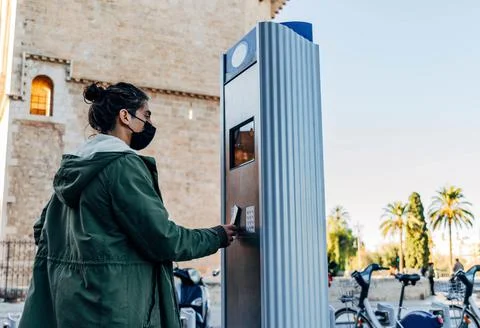 Young guy with face mask standing near a parking meter - new normal concept Stock Photos