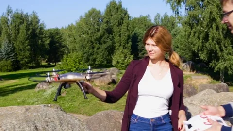 A young guy gik controls the drone girl teenager catches the quadcopter on the f Stock Footage 84796528