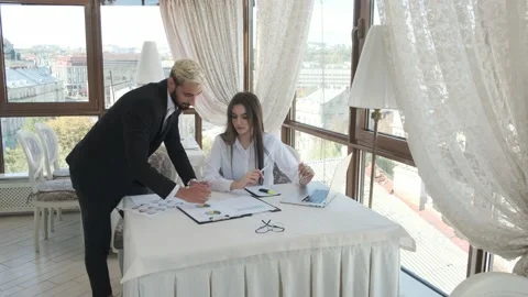 Young guy with girl looking at working papers, talking and smiling Stock Footage 130910544