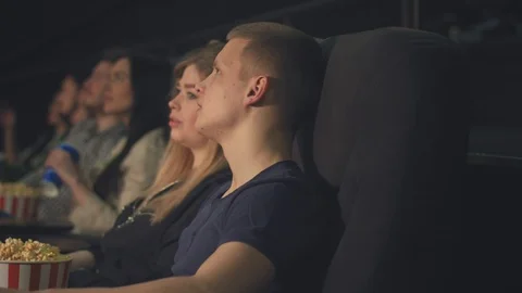 A young guy with a girl, talking while watching a movie in a movie theater an Stock Footage 95500072