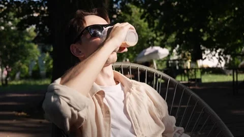 A young guy with glasses drinking a cold drink on a summer terrace Stock-Footage 280081718