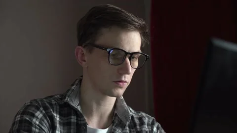 Young guy with glasses working on a black laptop at home Stock Footage 236690123