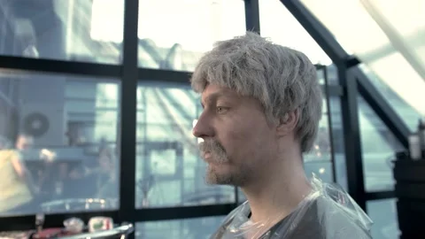 Young guy in a gray wig with a beard and mustache gets makeup before shooting Stock Footage 135992301