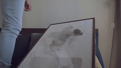 Young guy hangs a picture on the wall and his wife corrects it Stock Footage 113752157