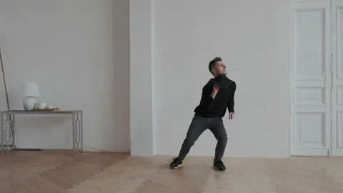 Young guy have fun at home. He dancing on the white wall background and wearing Stock Footage 107816628