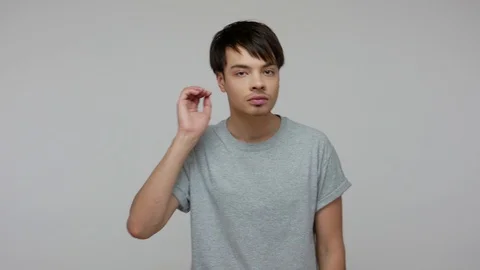 Young guy with hearing problems holding hand near his ear and listening around Stock Footage 124771835