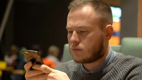 Young guy hipster drinks lemonade and types text on his smartphone 스톡 동영상 84525672
