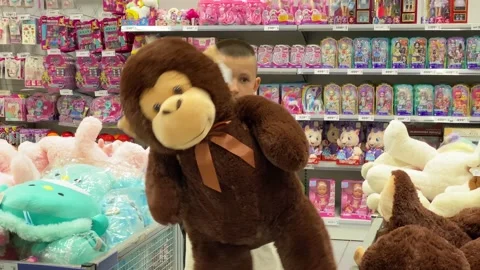 Young guy is holding a large soft brown monkey plush toy in his hands. Buying Stock Footage 205289540