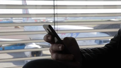 Young guy is holding smartphone sitting at airport indoor. Stock Footage 83029149