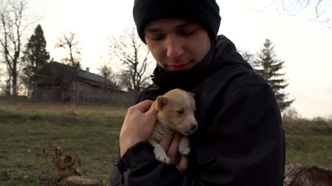 The young guy holds a small dog in his arms. The boy loves a small dog Stock Footage 122237225