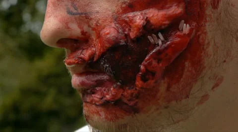 Young guy with a huge wound on his face says something, close-up, Halloween Stock Footage 68209403