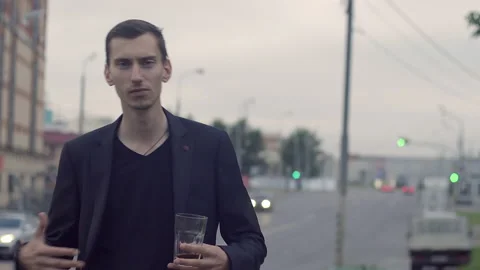 A young guy in a jacket holds a glass and dances Stockbeeldmateriaal 155945919