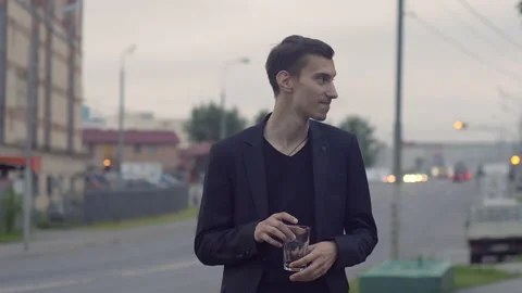 A young guy in a jacket holds a glass and dances Video stock 155945935