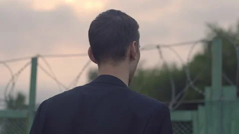 A young guy in a jacket looks over the fence Stock-Footage 155945870