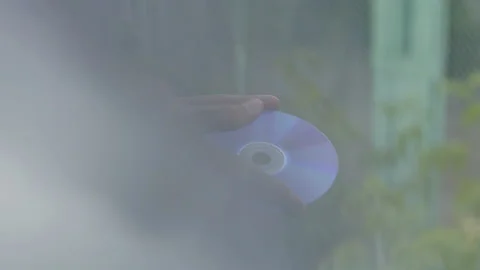 A young guy in a jacket is spinning a CD disk 스톡 동영상 155945944