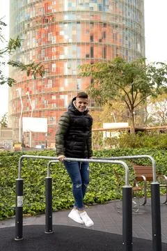 Young guy joining parallel bars outdoors while looking camera outdoors Stock Photos