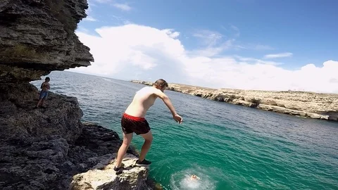 Young guy jump into the water from the ledge doing a flip Video stock 102020004