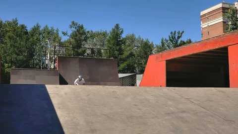 A young guy jumps and does tricks on a scooter in a skatepark Video stock 94142570