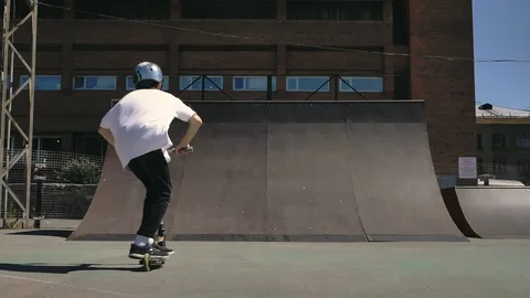 A young guy jumps and does tricks on a scooter in a skatepark 스톡 동영상 94142682