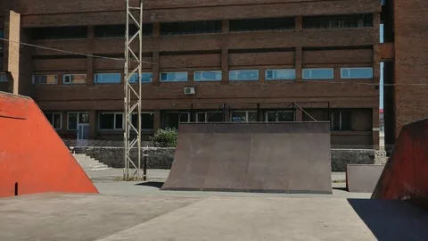 A young guy jumps and does tricks on a scooter in a skatepark Video stock 94142866