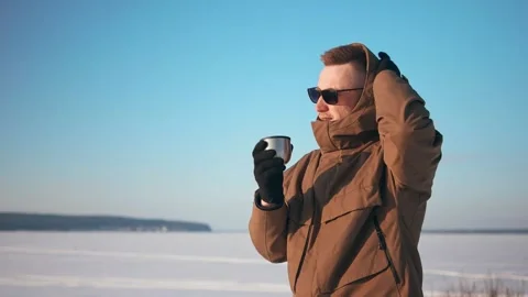 Young guy keeping warm using a mug of tea outdoors in winter. Stockbeeldmateriaal 150331300
