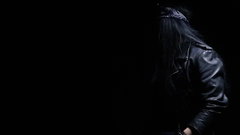 Young guy in leather jacket and bandana, with long hair shows the sign of the Stock Footage 102097055