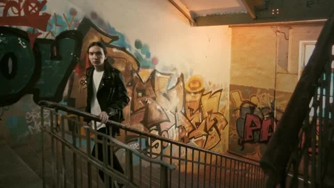 Young guy in a leather jacket with long hair climbs the stairs in a polozda Stock Footage 287914888