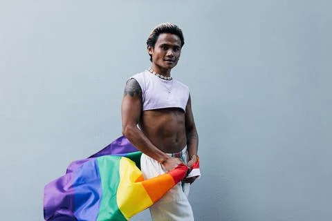 Young guy with LGBT flag posing at grey wall outdoors Stock Photos