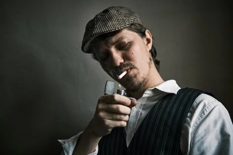 Young guy lights a cigarette, dressed in a retro style Stock Photos