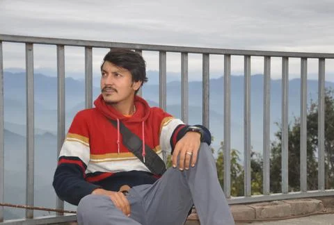 A young guy looking sideways, sitting by safety barrier  Stock Photos