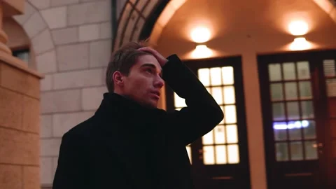 A young guy looks around standing on the street of a big city in the evening Stock Footage 157924735