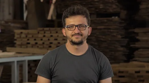 A young guy looks at the camera and smiles. glasses and a beard and a t-shirt Stock Footage 92314512
